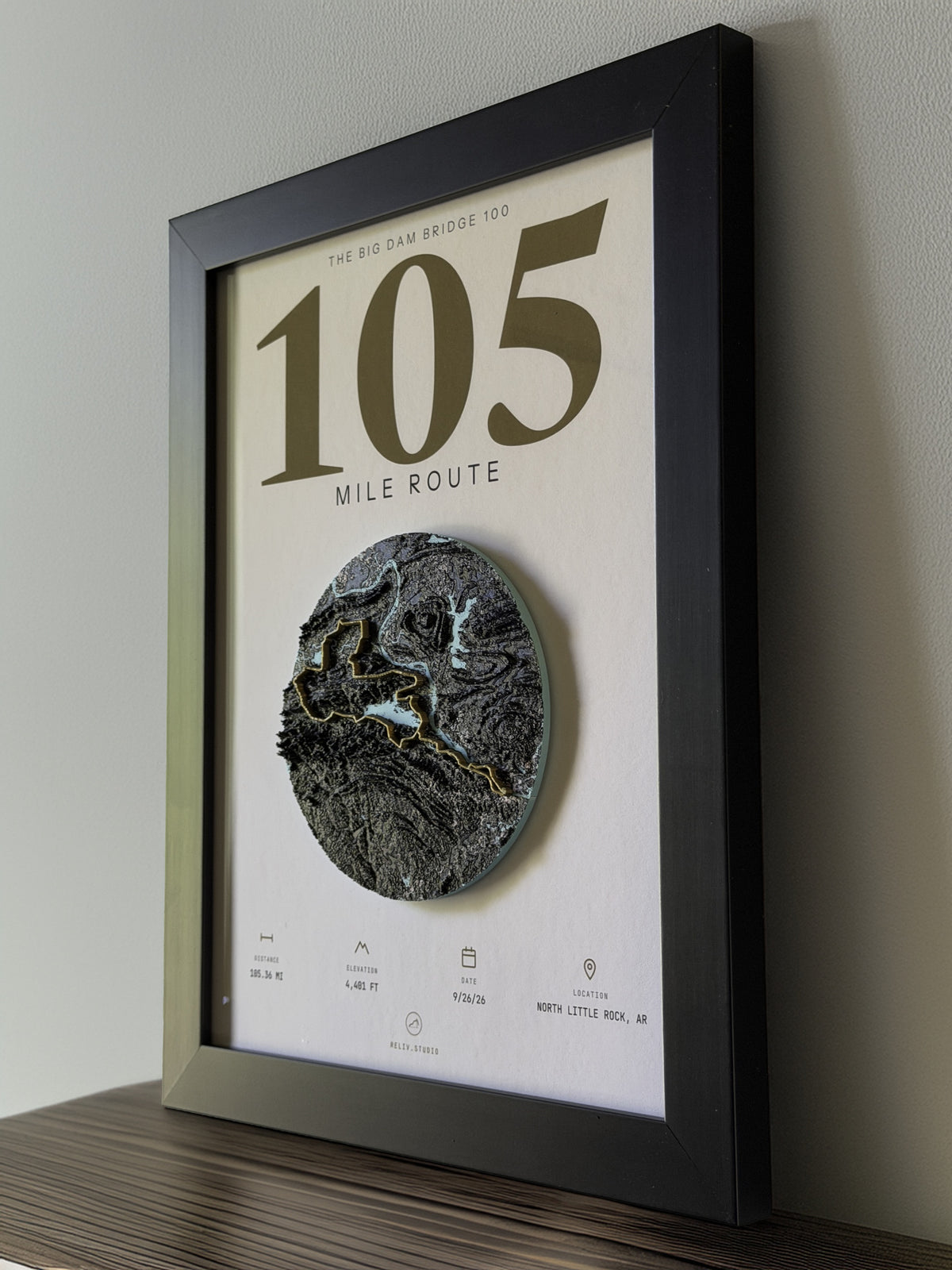 THE MARKER, 105 mile route of the Big Dam Bridge 100 — framed relief map viewed at an angle, showing the raised terrain and the brass route line