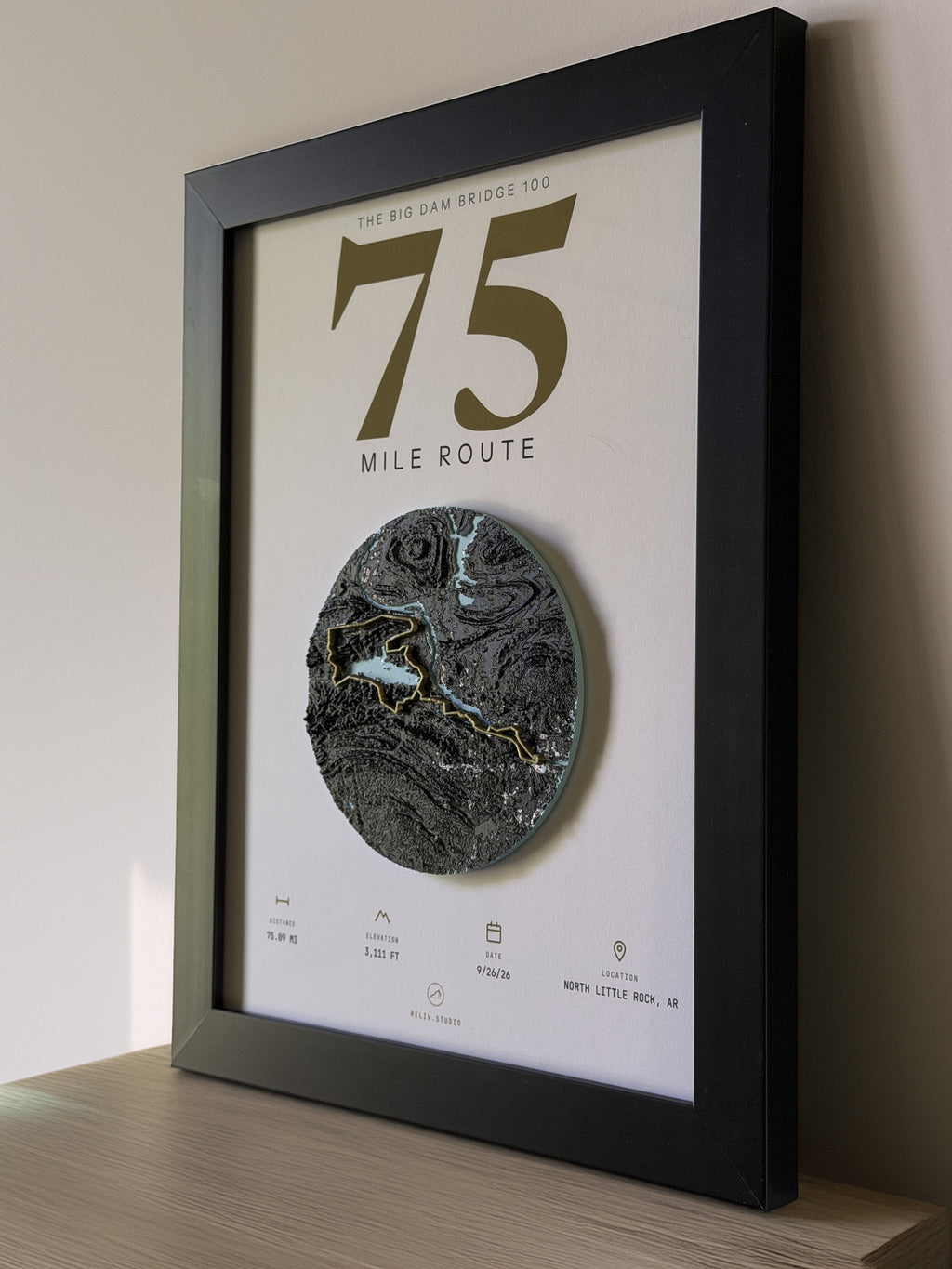 THE MARKER, 75 mile route of the Big Dam Bridge 100 — framed relief map viewed at an angle, showing the raised terrain and the brass route line